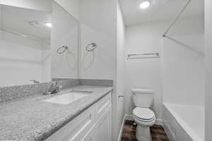 Bathroom with vanity, tub / shower combination, and dark wood-style floors