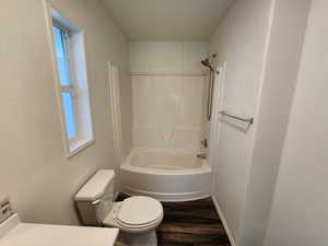 Full bath featuring vanity, shower / tub combination, dark wood-style flooring, and a textured wall