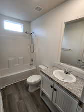 Bathroom featuring vanity, dark wood-style floors, and shower / tub combination