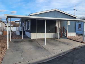 Manufactured / mobile home with a porch, a carport, and concrete driveway