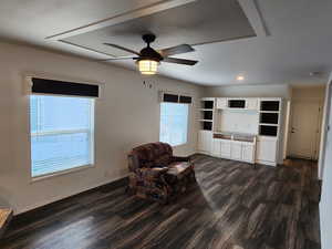 Sitting room with a ceiling fan and dark wood-style floors