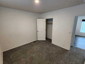 Unfurnished bedroom featuring dark colored carpet and a closet