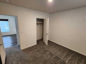 Unfurnished bedroom with dark colored carpet and a closet