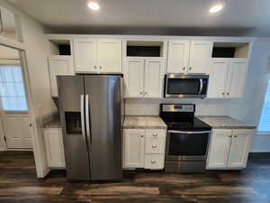 Kitchen with healthy amount of natural light, stainless steel appliances, white cabinetry, open shelves, and recessed lighting