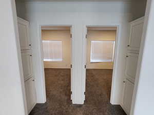 Hall featuring dark carpet and baseboards
