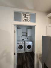 Washroom featuring cabinet space, dark wood-style floors, and washer and clothes dryer