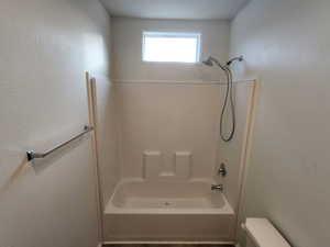 Bathroom featuring  shower combination and a textured wall