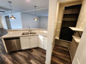 Kitchen featuring stainless steel dishwasher, dark wood finished floors, white cabinets, decorative light fixtures, and a peninsula