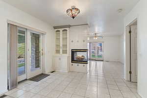 Unfurnished living room featuring a fireplace, built in shelves, light tile patterned flooring, and ceiling fan