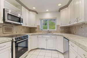 Kitchen with tile countertops, stainless steel appliances, white cabinets, light tile patterned flooring, and recessed lighting