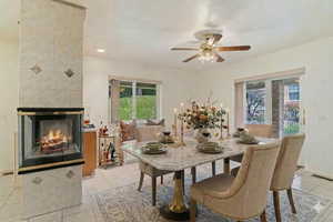 Dining room with ceiling fan, light tile patterned floors, a fireplace, and recessed lighting