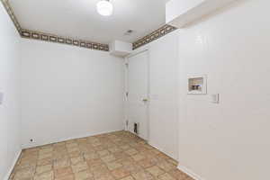 Laundry room featuring washer hookup, stone finish flooring, and a textured ceiling