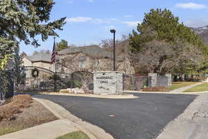 View of asphalt street featuring curbs, a gate, and a gated entry