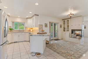 Kitchen featuring a peninsula, stainless steel fridge with ice dispenser, a breakfast bar area, a tile fireplace, and white cabinets