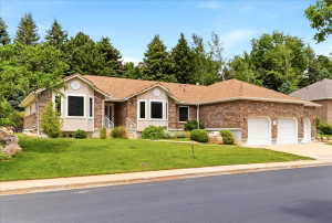 Ranch-style residence featuring a stone and stucco exterior, a two-car garage with white doors, and a well-maintained front lawn