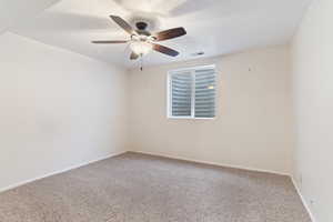 Carpeted empty room with ceiling fan and baseboards