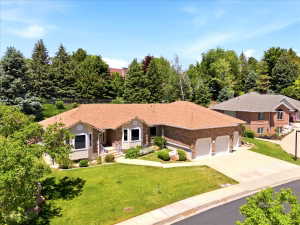 Expansive brick and stucco exterior with a multi-car garage, established landscaping, and a pitched roof