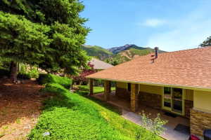 Stone veneer and siding exterior with a covered porch, set against a mountainous backdrop