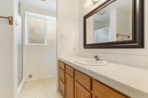 Full bathroom featuring light flooring, vanity, and a shower stall