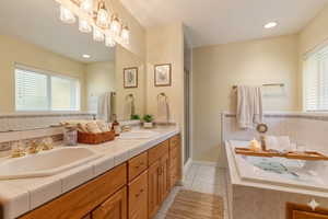 Full bathroom featuring double vanity, light tile patterned floors, a bath, recessed lighting, and a shower stall