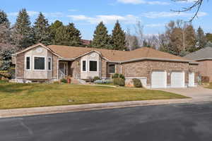 View of front of property with a front yard, brick siding, concrete driveway, and a garage