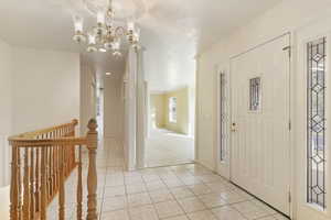 Foyer entrance with a chandelier and light tile patterned flooring