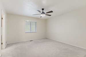 Carpeted spare room with a ceiling fan and baseboards