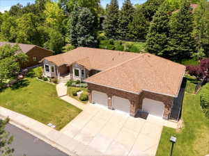 Brick-clad residence featuring a multi-car garage, concrete driveway, and a front walkway leading to the entrance