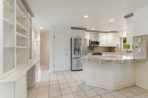 Kitchen with open shelves, stainless steel appliances, a breakfast bar, a peninsula, and white cabinetry