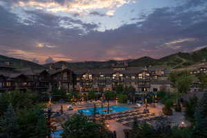 Pool at dusk featuring a community pool, a patio, a mountain view, and a pergola