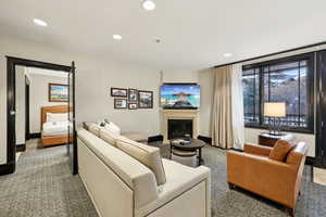 Carpeted living area featuring a glass covered fireplace and recessed lighting