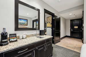 Kitchen with light stone counters, dark cabinetry, light colored carpet, light tile patterned floors, and recessed lighting