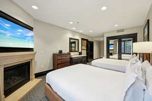 Carpeted bedroom with access to exterior, recessed lighting, a fireplace with flush hearth, and french doors