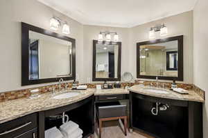 Bathroom with double vanity, a shower stall, light tile patterned floors, and backsplash