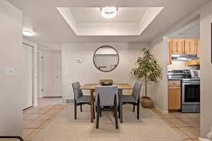 Dining space featuring light tile patterned floors and a raised ceiling