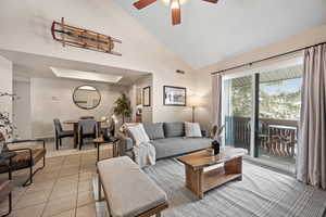 Living area with light tile patterned floors, high vaulted ceiling, and a ceiling fan