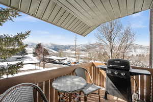 Snow covered back of property featuring a mountain view and grilling area