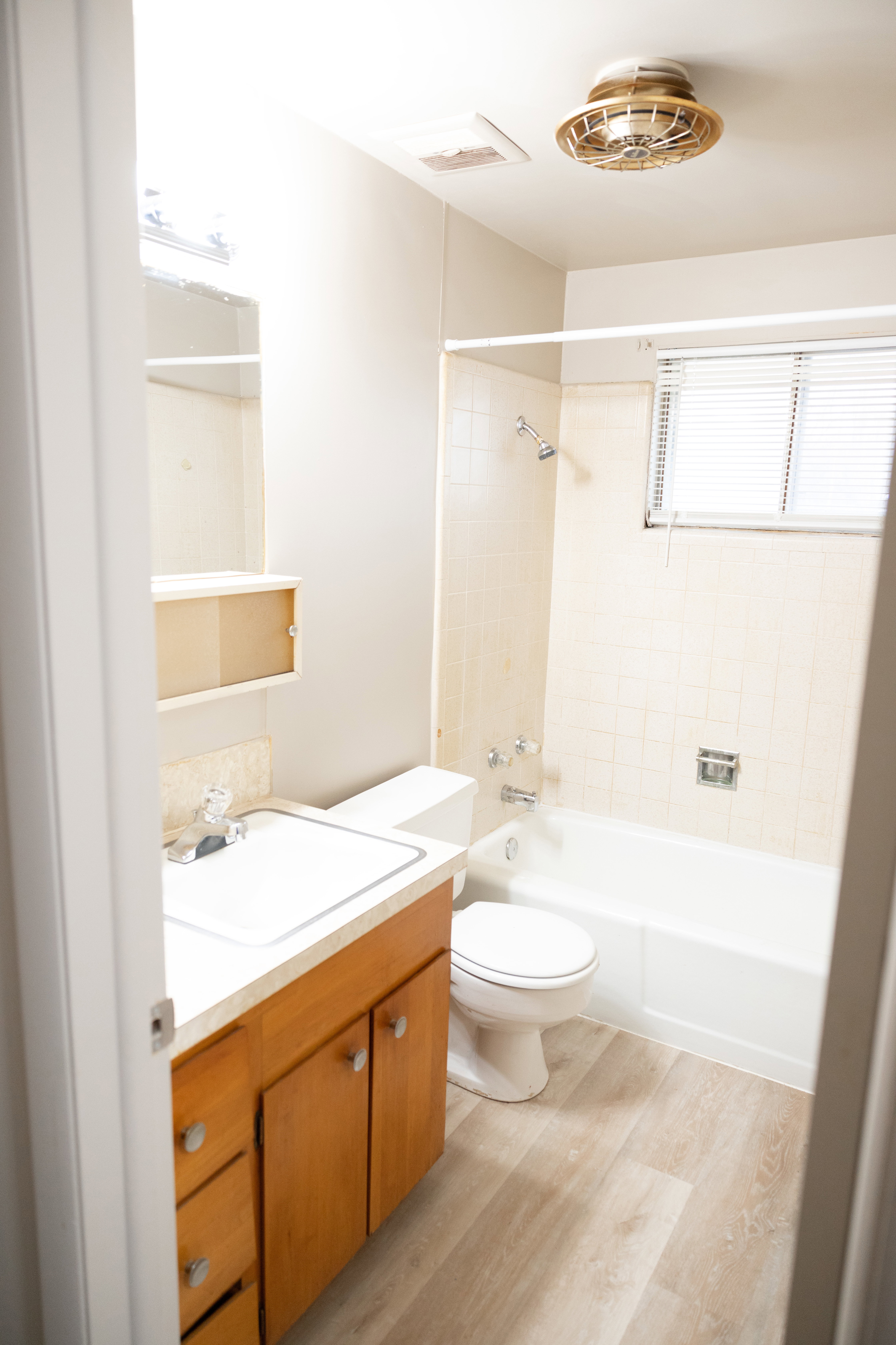 Full bathroom with washtub / shower combination, vanity, and light wood-style flooring
