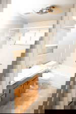 Full bathroom with washtub / shower combination, vanity, and light wood-style flooring