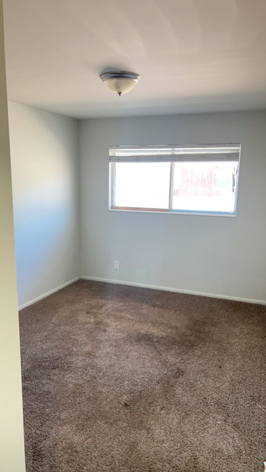 Spare room featuring dark colored carpet and baseboards