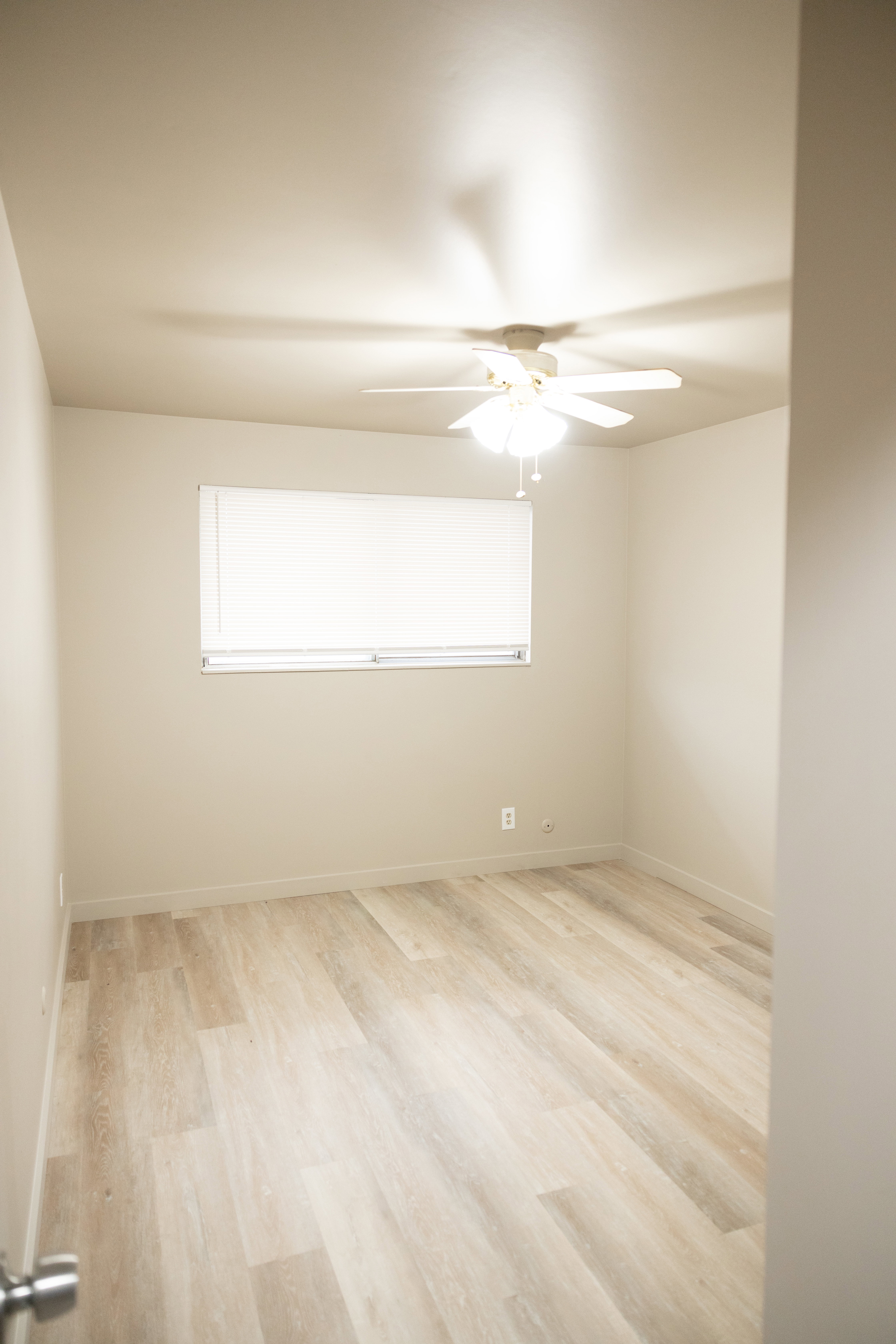 Empty room with a ceiling fan and light wood-style flooring