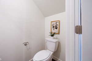 Bathroom featuring toilet and lofted ceiling