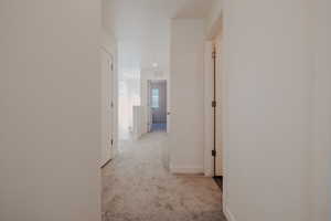 Hall with light colored carpet and baseboards