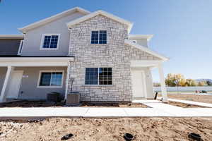 View of front facade with stone siding, stucco siding, and a porch