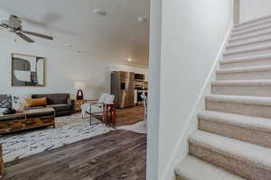 Living room featuring dark wood-type flooring, stairway, recessed lighting, and ceiling fan