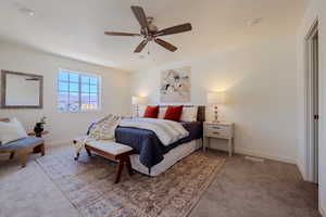 Carpeted bedroom with a ceiling fan and baseboards