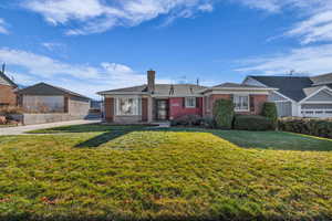 View of front of property with brick siding, a chimney, and a front lawn