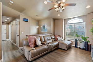 Living area featuring wood finished floors, recessed lighting, vaulted ceiling, a ceiling fan, and a textured ceiling