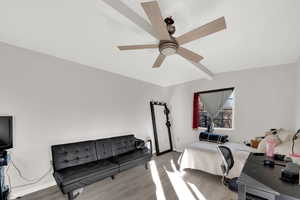 Bedroom with beam ceiling, wood finished floors, and a ceiling fan