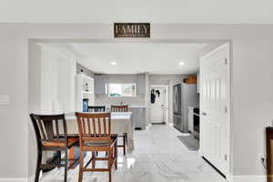 Dining area featuring light marble finish floors and recessed lighting